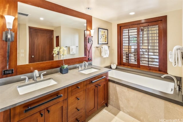 bathroom with a washtub, tile patterned floors, and vanity