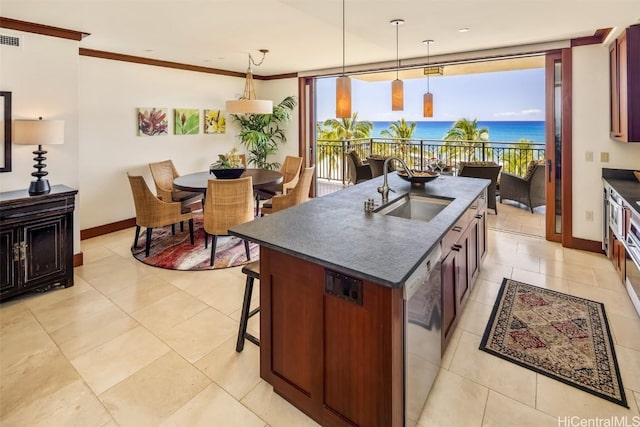 kitchen with stainless steel dishwasher, decorative light fixtures, an island with sink, a water view, and sink