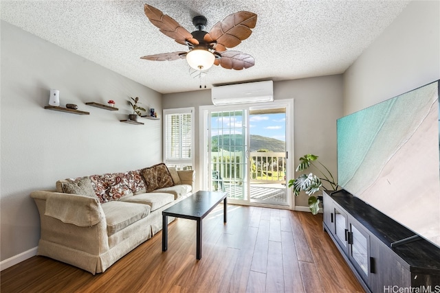 living room featuring ceiling fan, wood-type flooring, a textured ceiling, and a wall unit AC