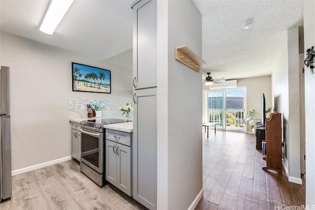 kitchen featuring ceiling fan, appliances with stainless steel finishes, gray cabinetry, and light hardwood / wood-style flooring