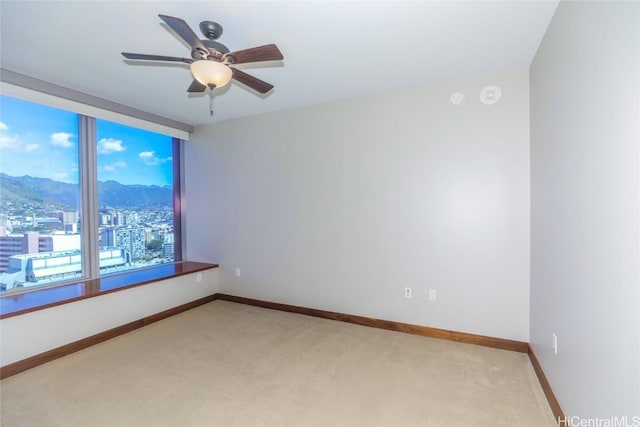 carpeted empty room with a mountain view and ceiling fan