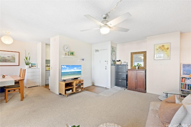 carpeted living room featuring ceiling fan and a textured ceiling