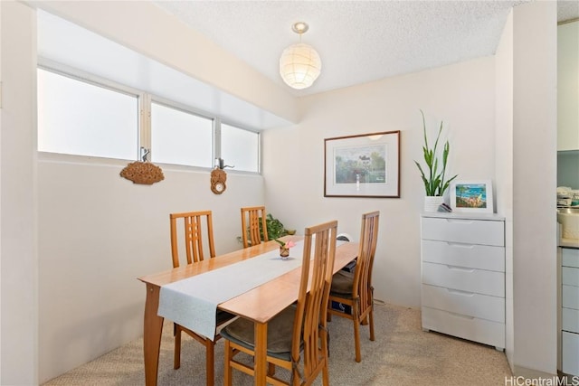 dining space with light colored carpet and a textured ceiling