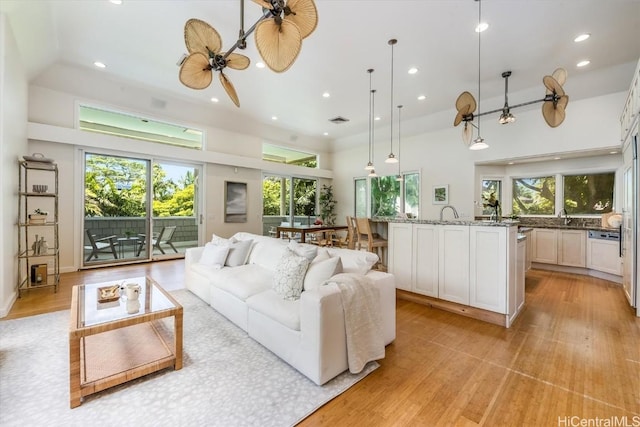 living room with ceiling fan, plenty of natural light, and light wood-type flooring