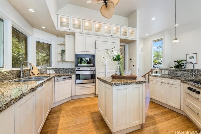 kitchen with sink, white cabinetry, pendant lighting, and oven