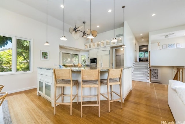 kitchen with light stone counters, white cabinets, built in appliances, and hanging light fixtures