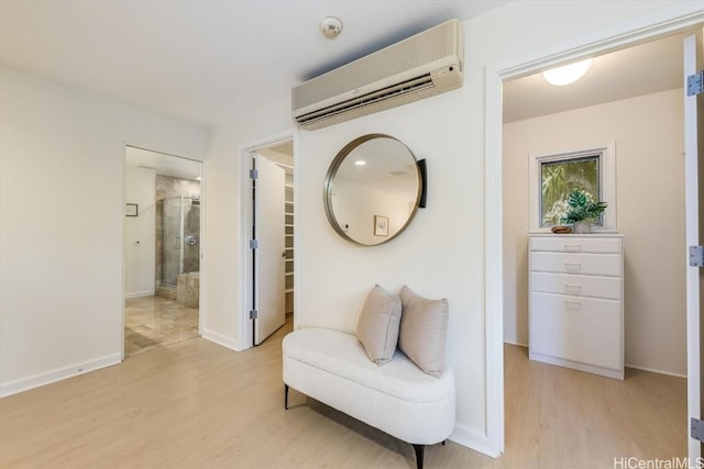 sitting room with a wall unit AC and light hardwood / wood-style floors