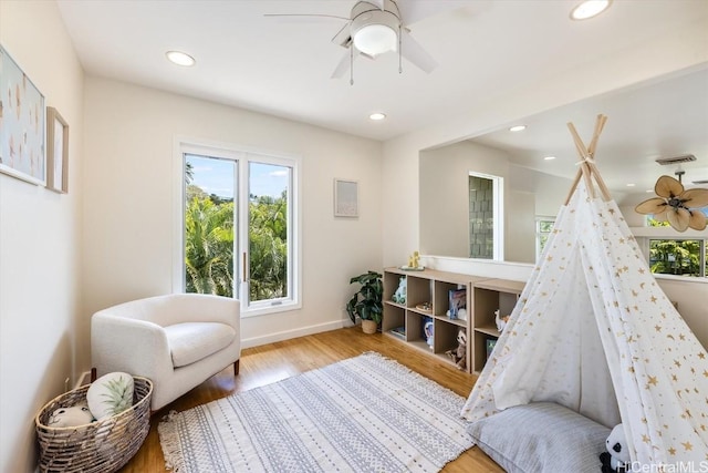 rec room with light hardwood / wood-style floors and ceiling fan