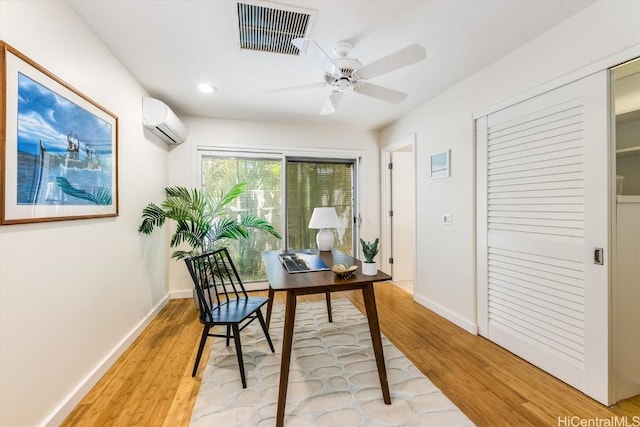 office space featuring an AC wall unit, ceiling fan, and light hardwood / wood-style flooring