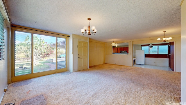 unfurnished living room with a notable chandelier, a textured ceiling, and plenty of natural light