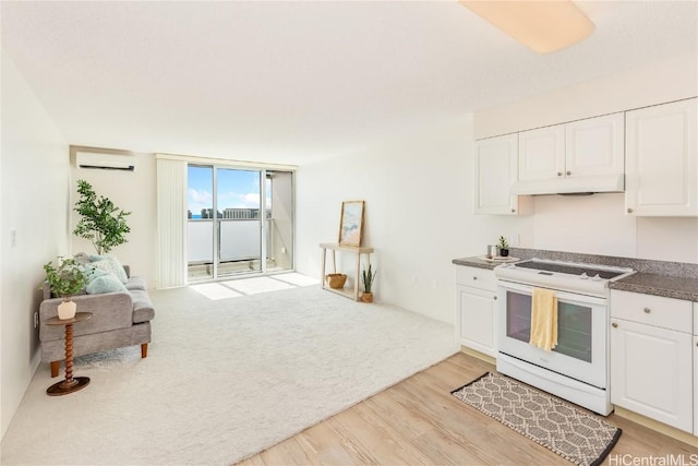 kitchen with light wood-type flooring, white range with electric stovetop, an AC wall unit, and white cabinetry