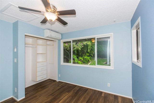 unfurnished bedroom featuring a textured ceiling, ceiling fan, a closet, a wall unit AC, and dark wood-type flooring