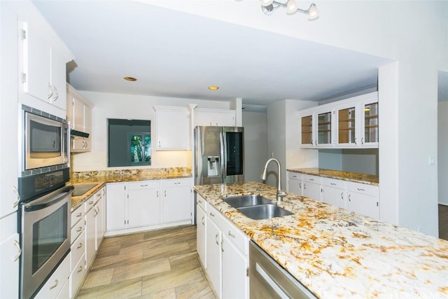 kitchen featuring white cabinets, stainless steel appliances, light stone countertops, and sink