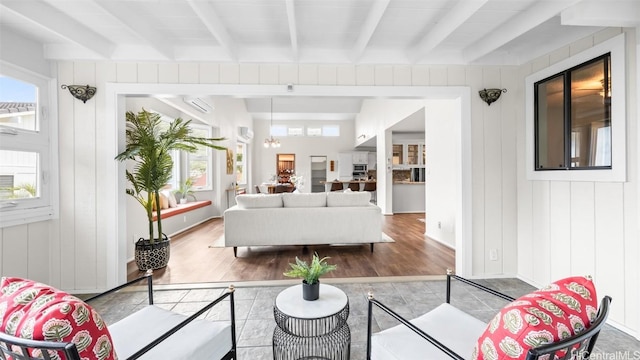 living room featuring beam ceiling, wooden walls, and wood finished floors