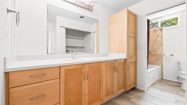 full bath with toilet, a textured ceiling, vanity, and wood finished floors