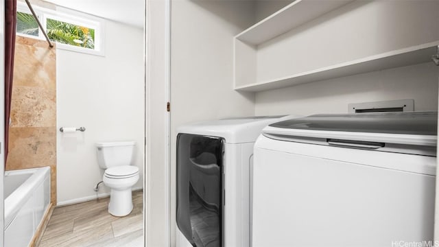 laundry area featuring baseboards, light wood-style floors, independent washer and dryer, and laundry area