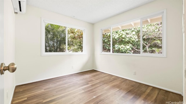 unfurnished room featuring a wall mounted air conditioner, baseboards, and wood finished floors