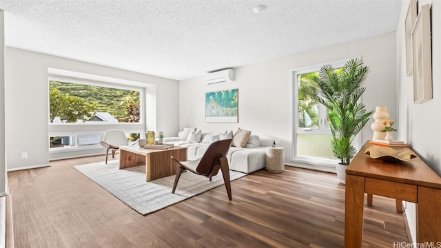 living room with a wealth of natural light, a textured ceiling, wood finished floors, and a wall mounted AC