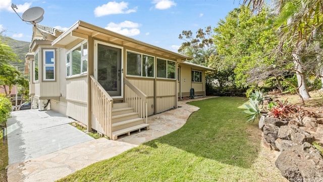 rear view of property featuring a yard and entry steps