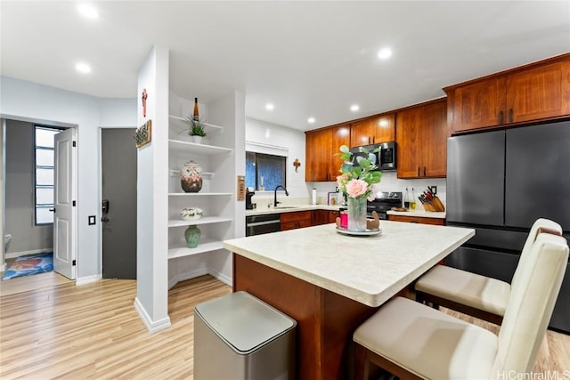 kitchen with sink, a breakfast bar, stainless steel appliances, light hardwood / wood-style floors, and a kitchen island