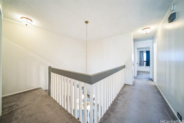 hall with carpet flooring, a textured ceiling, and baseboards