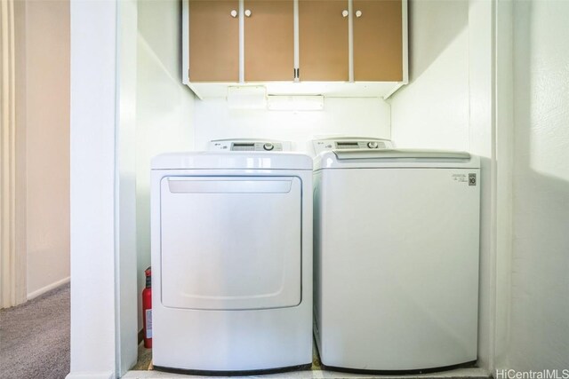 clothes washing area with separate washer and dryer, carpet flooring, and cabinet space