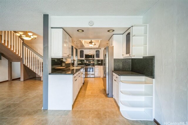 kitchen featuring dark countertops, appliances with stainless steel finishes, white cabinetry, open shelves, and a sink