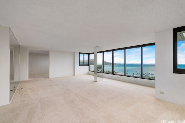 carpeted empty room featuring a textured ceiling and a water view