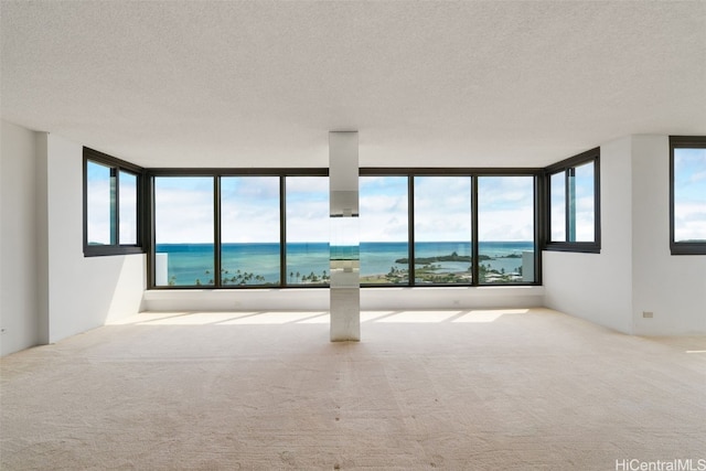 carpeted empty room featuring a textured ceiling and a water view