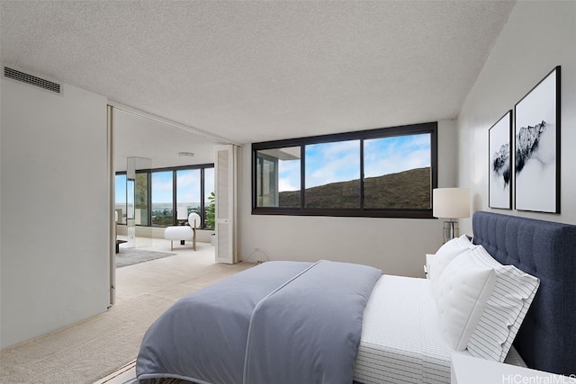 bedroom featuring a textured ceiling and light colored carpet