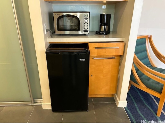 bar featuring dark tile patterned flooring and dishwasher