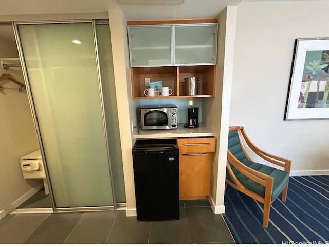 bar with fridge and dark tile patterned floors