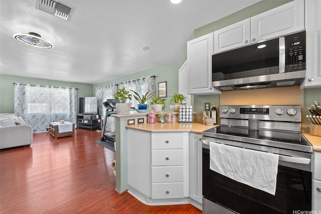 87-1980 Pakeke St Unit J, Waianae, HI 96792 - kitchen featuring stainless steel appliances, open floor plan, dark wood-type flooring, a peninsula, and white cabinets