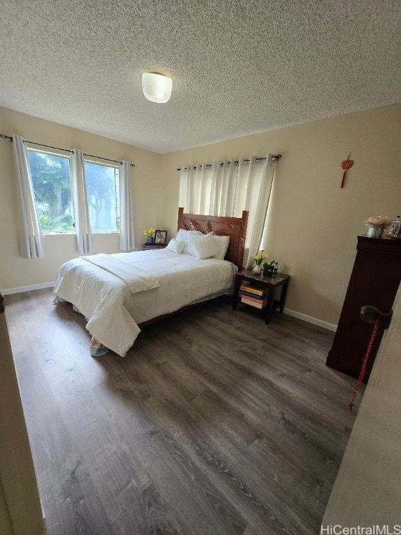 bedroom with a textured ceiling and dark hardwood / wood-style flooring