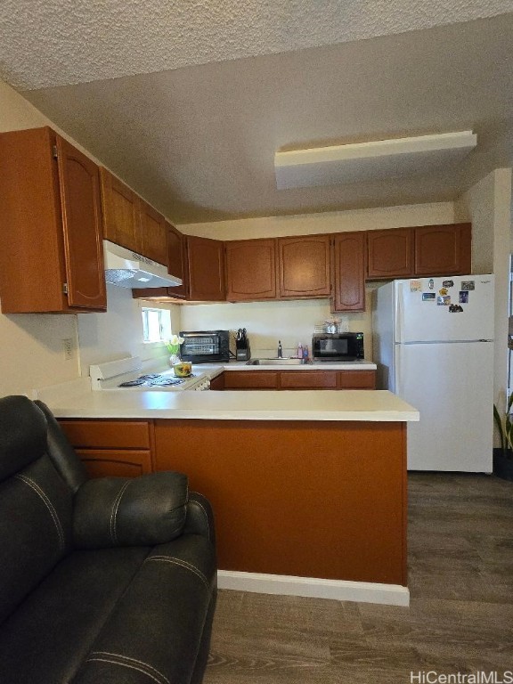 kitchen featuring a textured ceiling, sink, kitchen peninsula, and white appliances