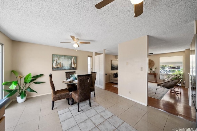 tiled dining area with a textured ceiling and ceiling fan