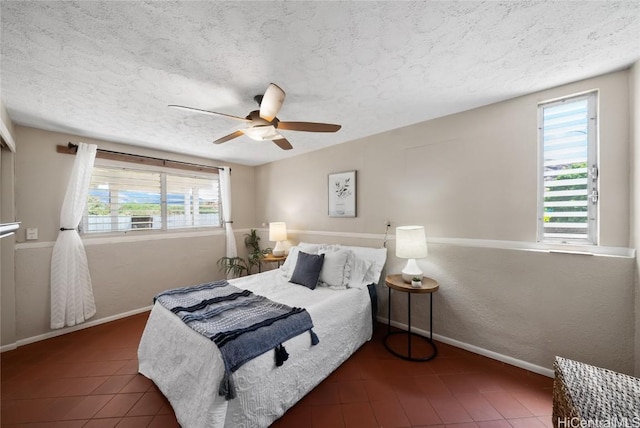 bedroom featuring ceiling fan, a textured ceiling, and multiple windows