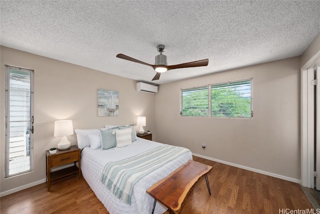 bedroom featuring a textured ceiling, dark hardwood / wood-style floors, a wall unit AC, and ceiling fan