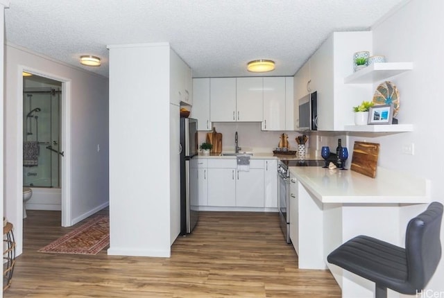 kitchen with white cabinetry, stainless steel appliances, light wood-type flooring, a textured ceiling, and sink