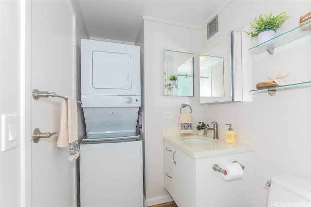 bathroom featuring toilet, vanity, and stacked washer and clothes dryer