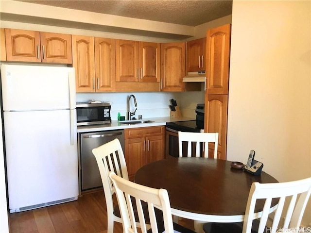 kitchen featuring stainless steel appliances, dark wood-type flooring, a textured ceiling, and sink