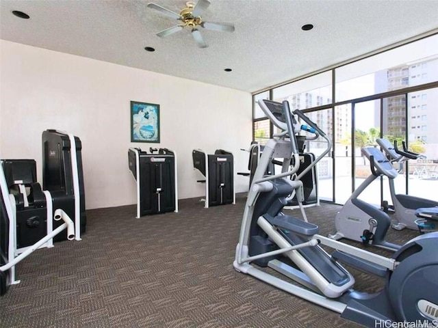 gym with a textured ceiling, ceiling fan, dark carpet, and a wall of windows