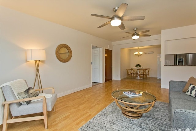 living room featuring ceiling fan with notable chandelier and light hardwood / wood-style floors