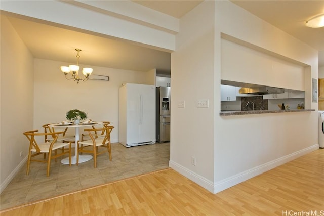 kitchen with stainless steel refrigerator with ice dispenser, white fridge, a notable chandelier, pendant lighting, and light hardwood / wood-style floors