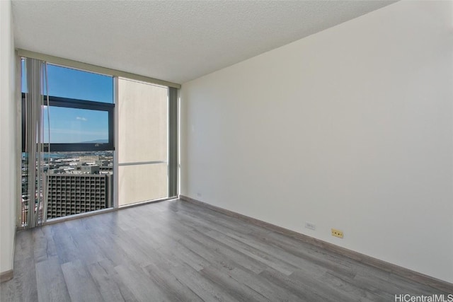 unfurnished room with a textured ceiling, hardwood / wood-style flooring, and expansive windows