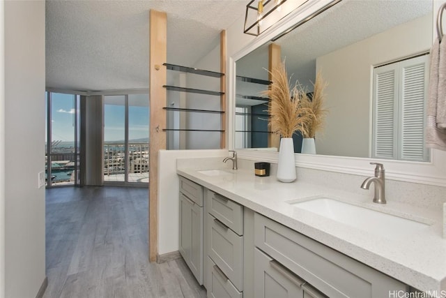 bathroom with a textured ceiling, a wall of windows, vanity, and hardwood / wood-style floors