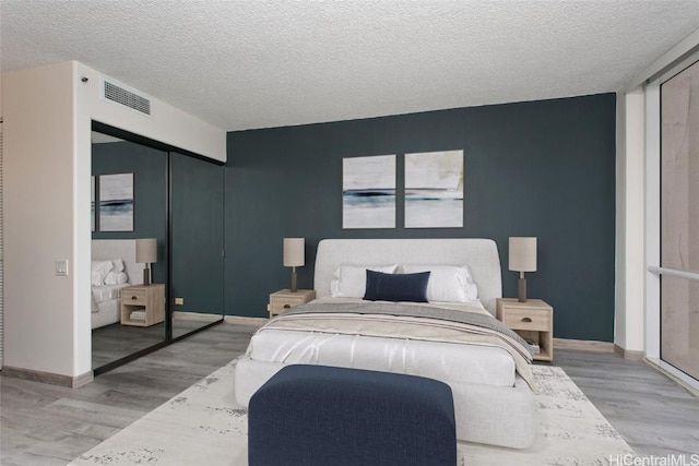 bedroom with a textured ceiling and light hardwood / wood-style flooring