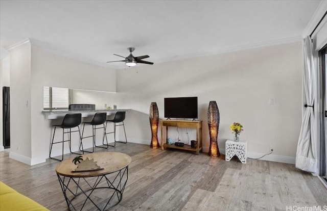 living room with a ceiling fan, baseboards, and wood finished floors