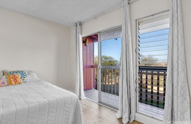 bedroom with a textured ceiling, wood finished floors, and access to exterior