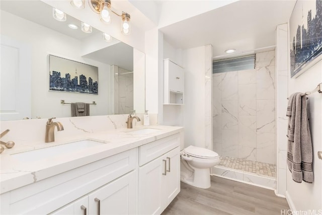 bathroom featuring hardwood / wood-style flooring, vanity, toilet, and a tile shower